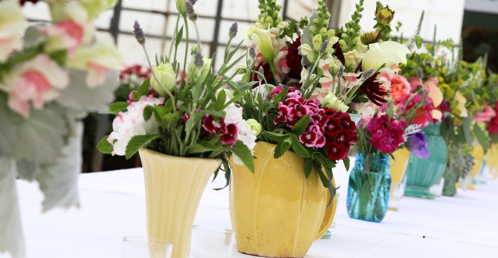 Imagine a table set for 40 . . . inside a flower-filled greenhouse. Vintage vases overflowing with just-picked blooms adorn the table and a locally-grown menu is is served.