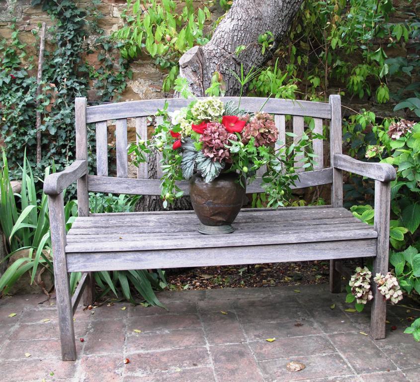 A rustic wooden garden bench, a perfect place to display and photograph my Tuscan bouquet in a timeworn copper vessel.