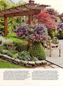 At the base of each post, there is a clipped boxwood to visually anchor the structure. Hanging baskets add late summer color and drama.