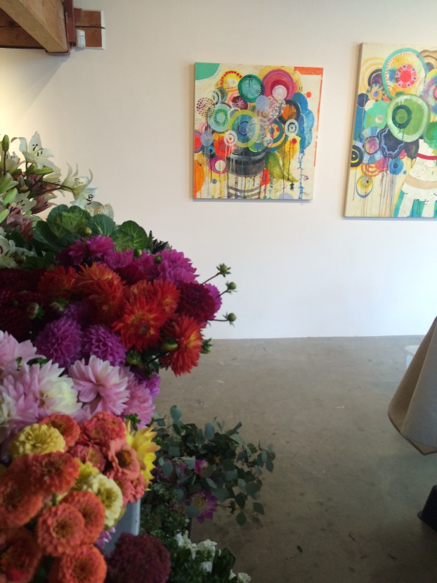 Flowers and art in juxtaposition. In the background, the paintings of Liz Tran.