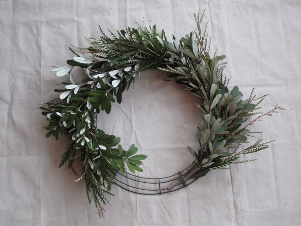 Continue working around the wreath base to attach individual foliage bundles.