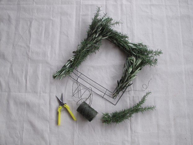 Then I began to attach each bundle around the frame, making sure to alternate types of foliage (rosemary/olive), overlapping to hide the tied ends.