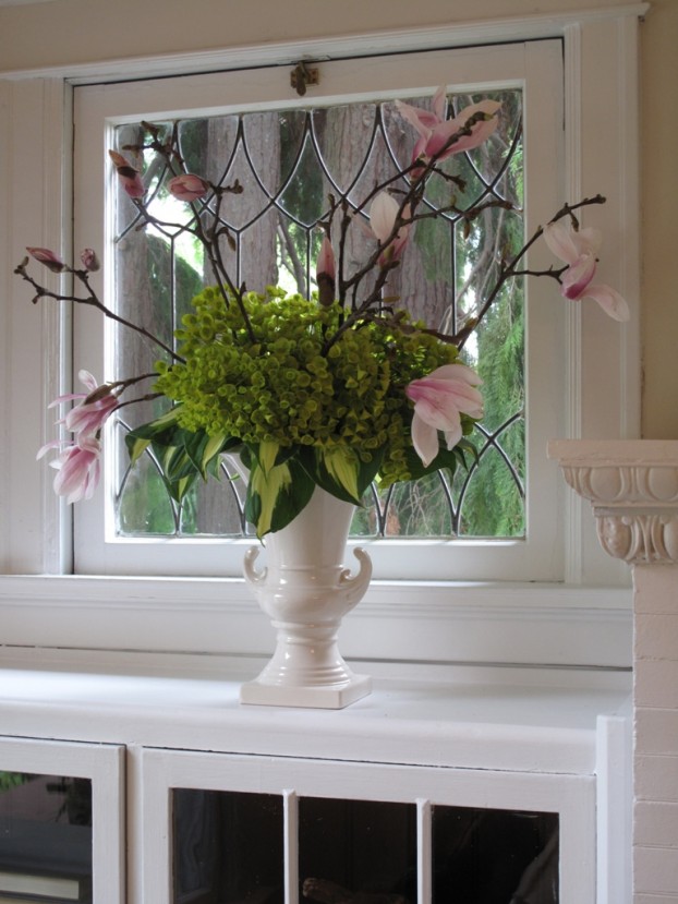 The acid green of variegated hostas and euphorbia create a "skirt" effect for flowering magnolia branches.